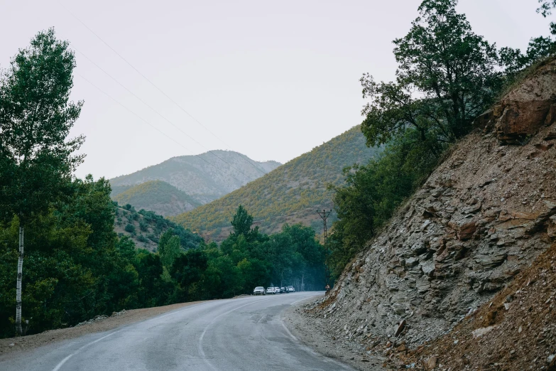 cars are driving on the road near hills