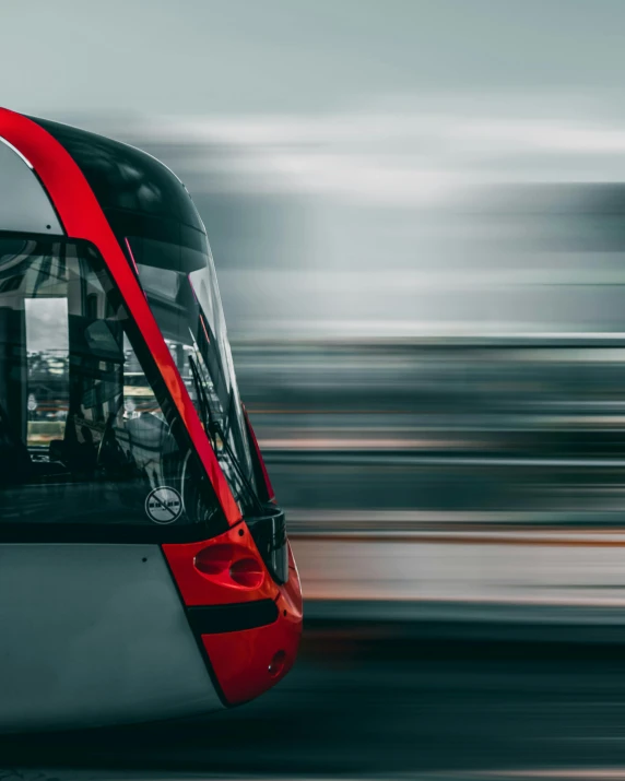 a red and white public transportation train is moving quickly