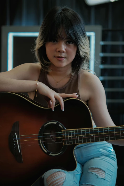 a young woman with short hair sitting with her guitar
