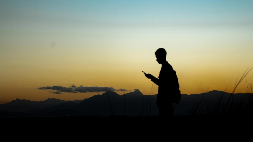 a silhouette of a person holding a cell phone in the dark