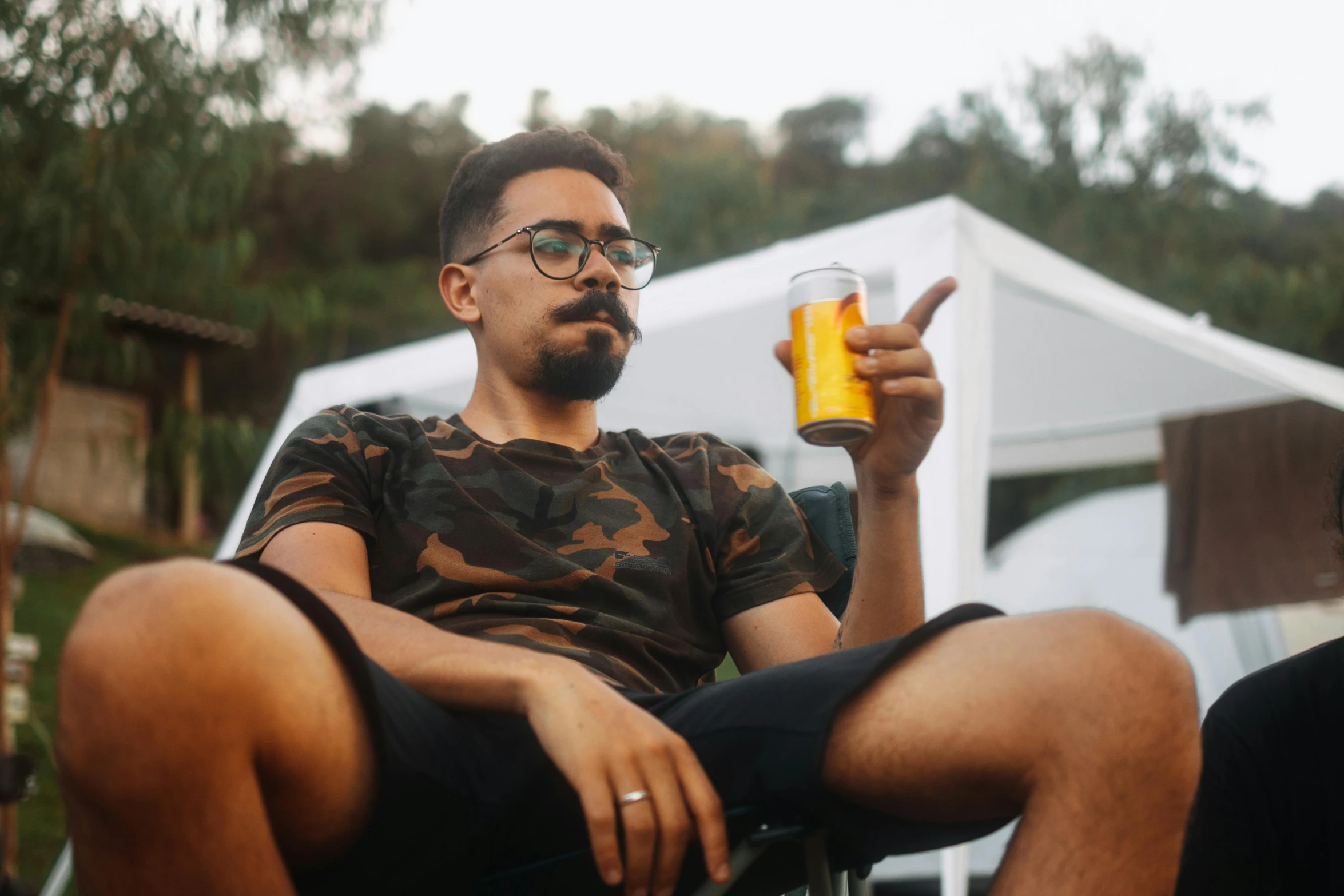 a man with a beard sitting in a chair holding a glass