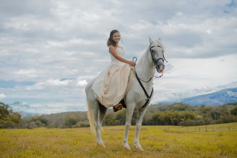 there is a woman wearing a long dress riding on the back of a horse