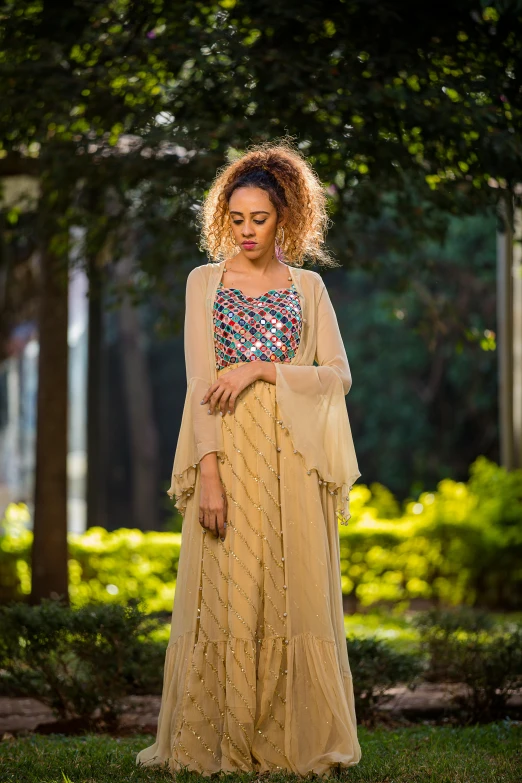 a woman wearing a long tan skirt and top with beaded embellishment