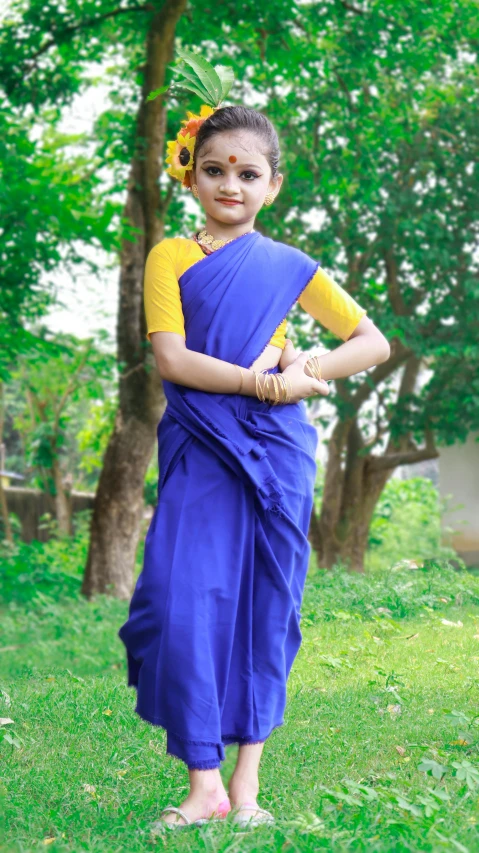a girl wearing an indian style saree standing on a field