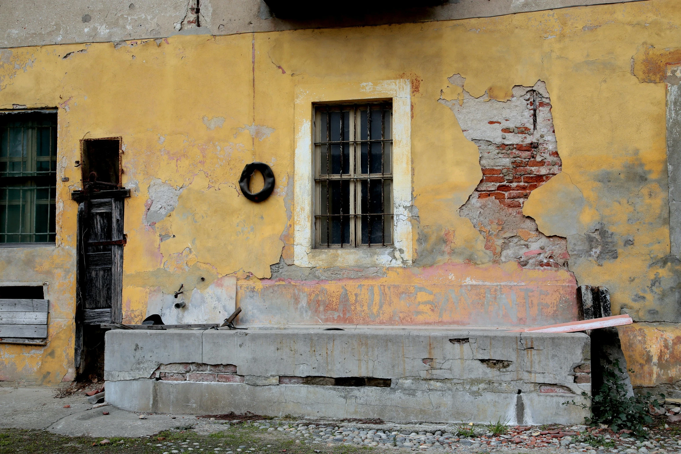 an old cement bench sits on front of an abandoned building