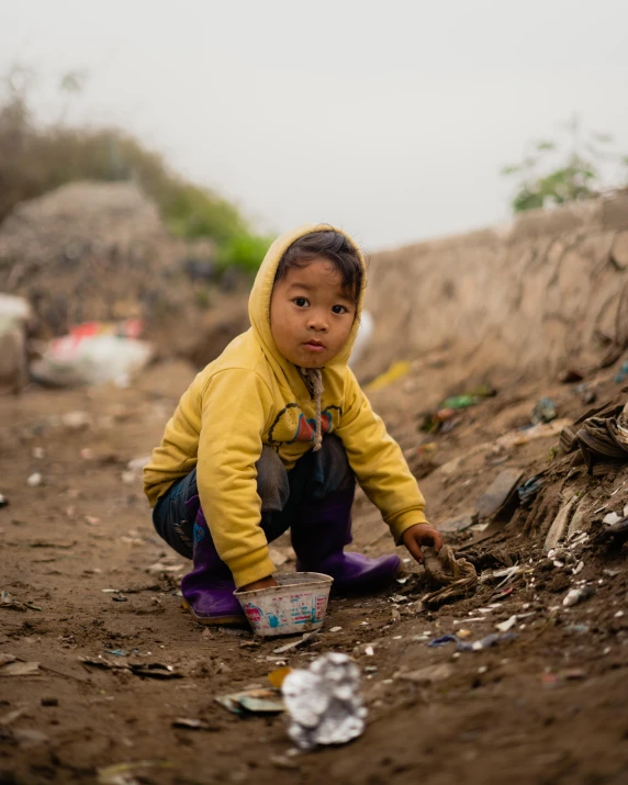 a  squatting down on the ground with a bucket in her hand