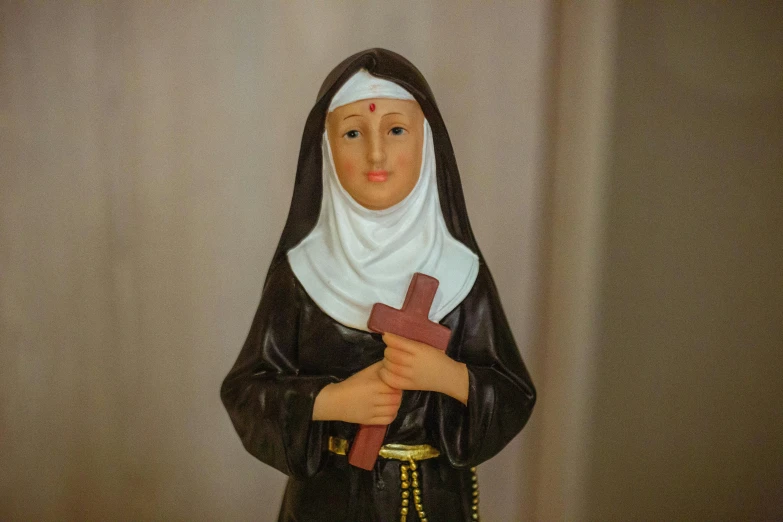 a statue of the virgin mary is featured against a beige background