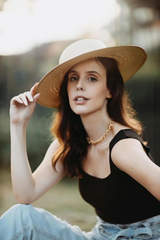 a beautiful woman wearing a large hat sitting outside