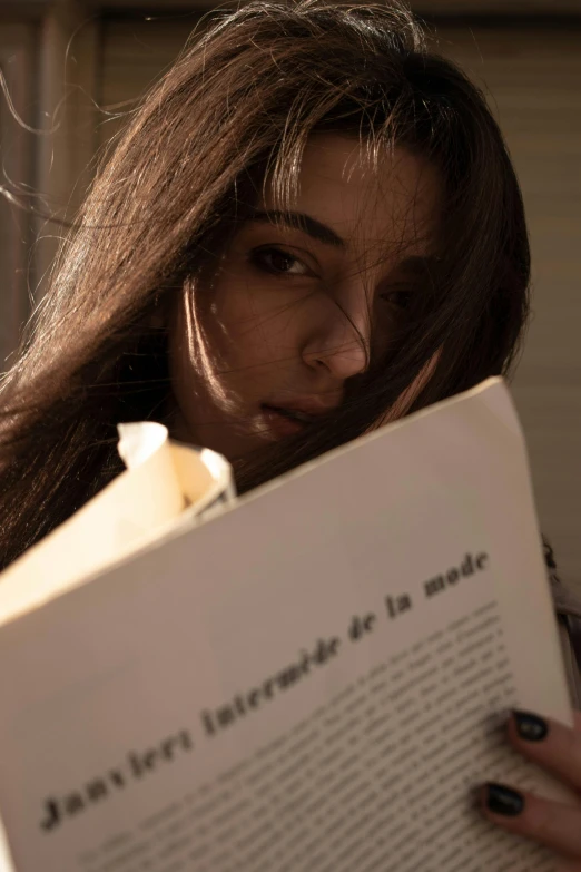 a woman holding an open book with her head slightly hidden