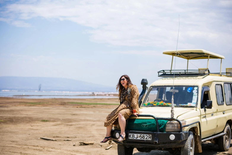 a woman poses in front of an off road vehicle