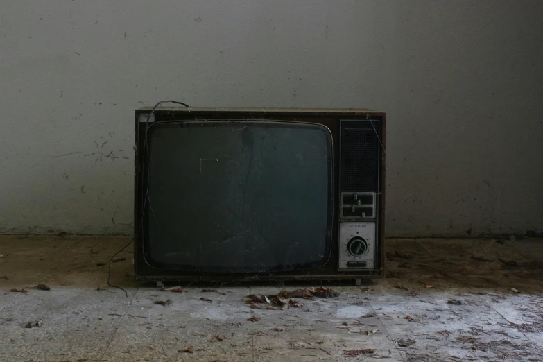 an old television on the ground in front of a wall