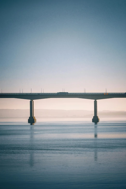 a bridge in the water with a blue sky and a light house above it