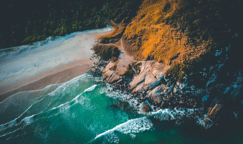 aerial view of a beach near an ocean with lots of waves