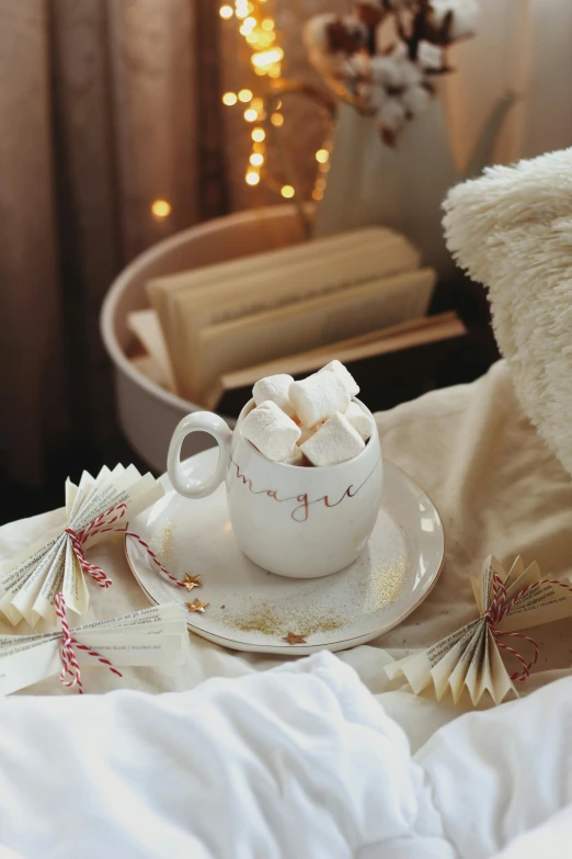 a cup with marshmallows in it sitting on a bed