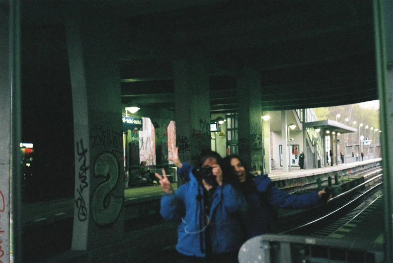 people stand with their cellphones at a train station