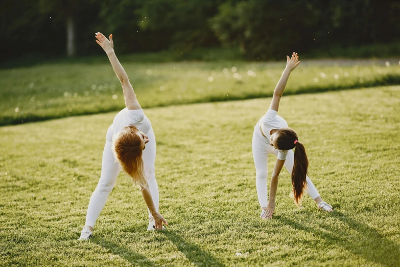 two young women standing in a field doing yoga