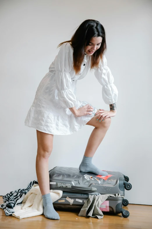 girl standing on suitcase with shoes on top