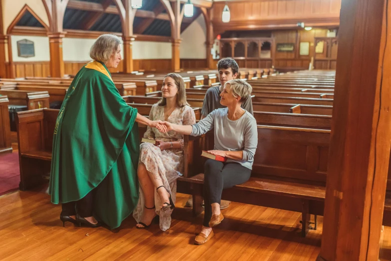 people in a church sitting on benches shaking hands