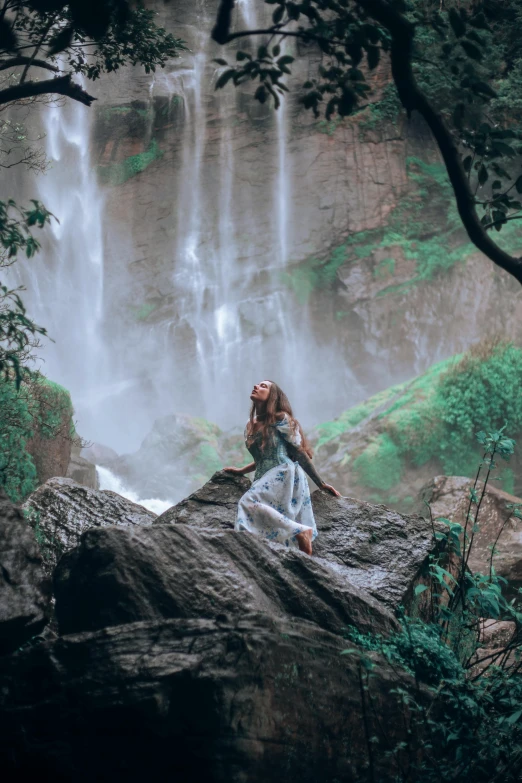 woman sitting on a rock near a waterfall