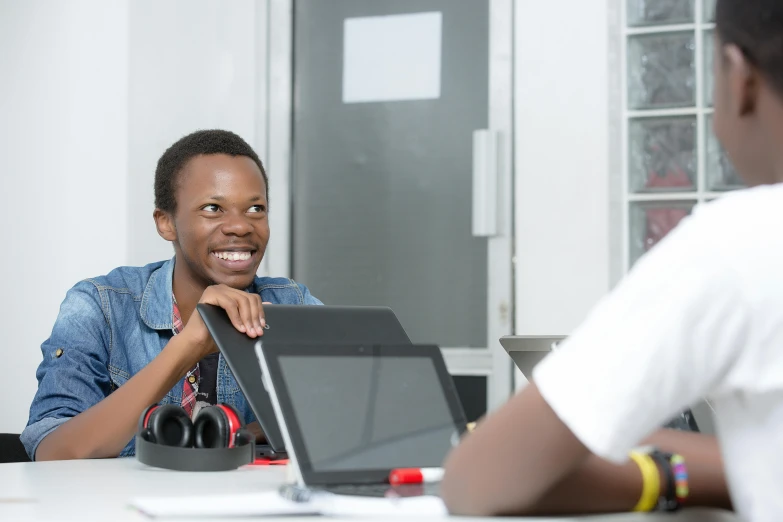 a person sits at a desk and holds up a laptop