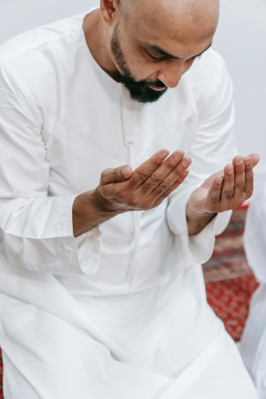 a man wearing a white outfit is praying