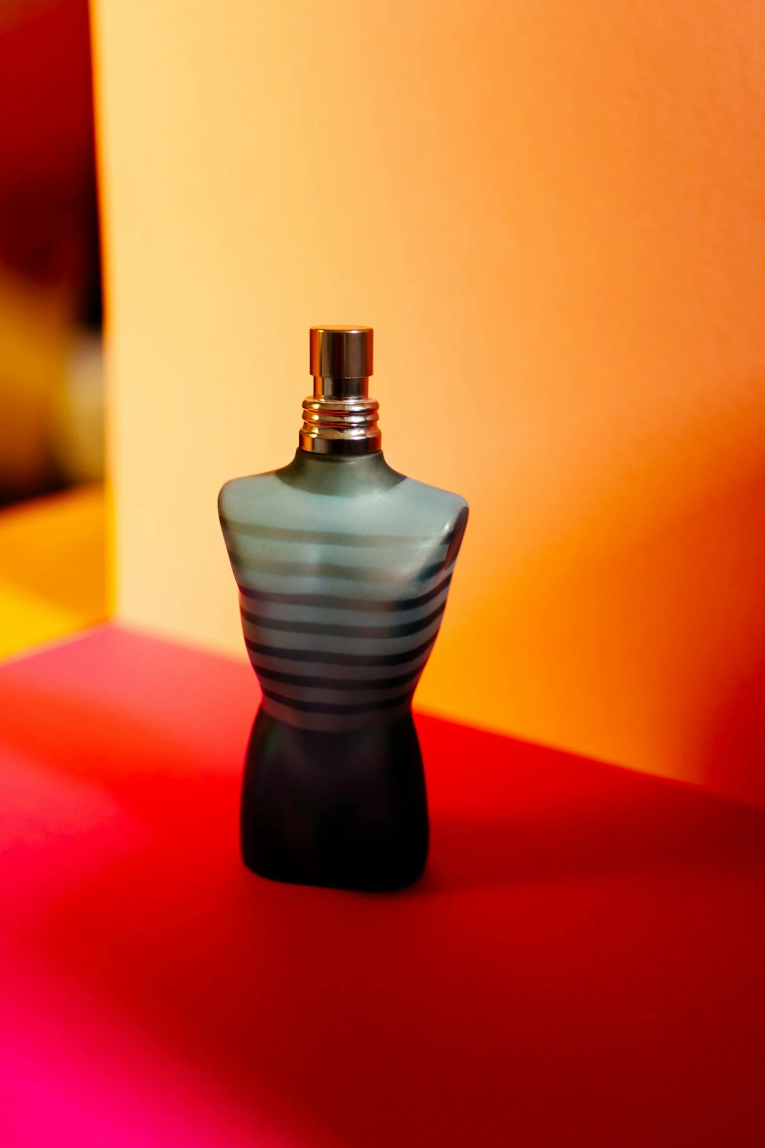 the perfume bottle is casting a shadow on a bright red surface