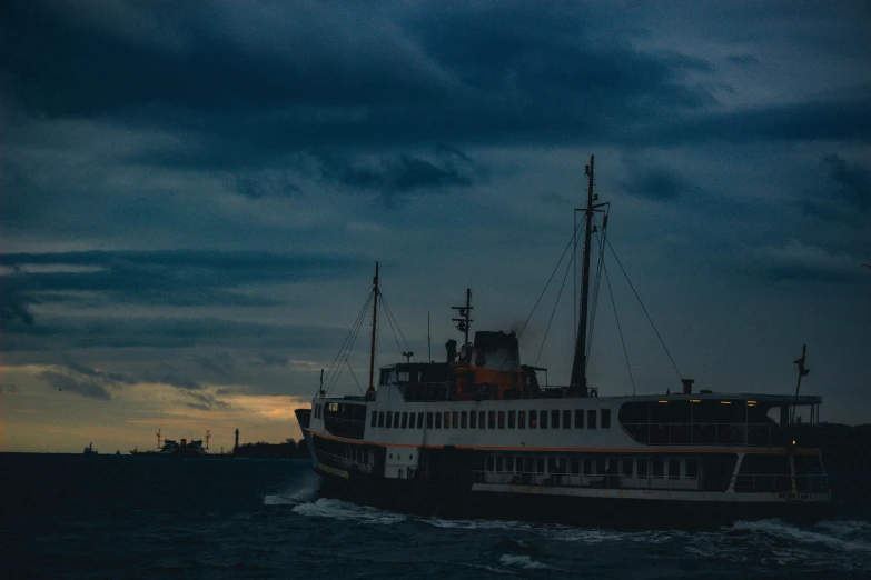 a ferry is docked at dusk with dark clouds