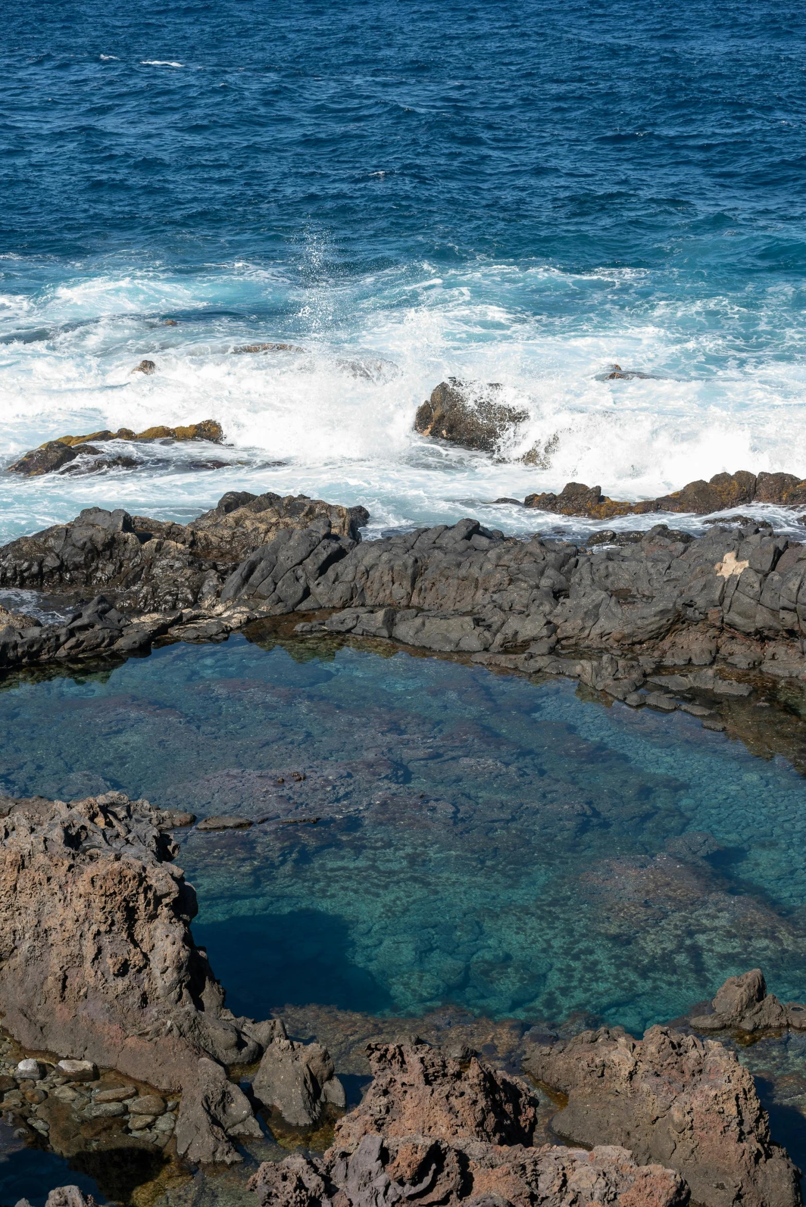 a rocky coastline with a pool full of water and some waves