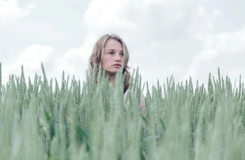 woman stands in tall grass by itself looking around