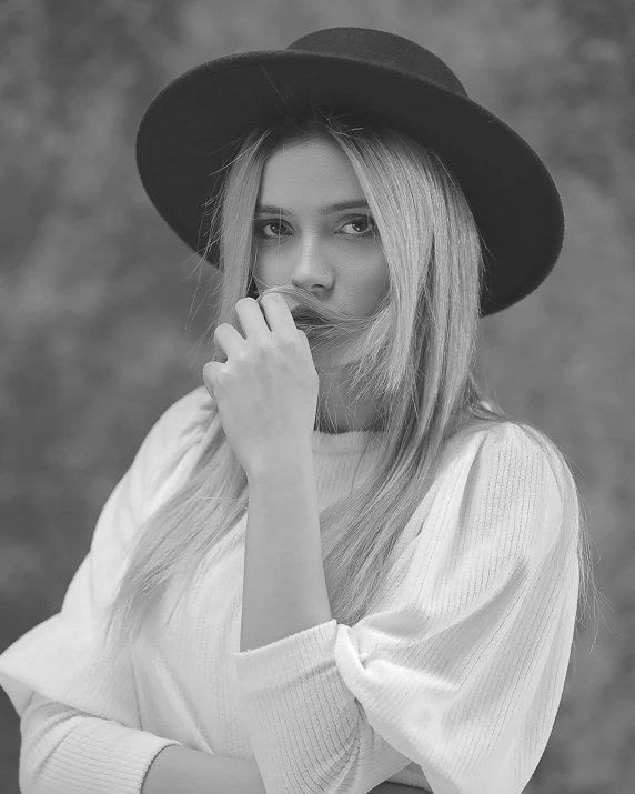 a woman wearing a hat is blowing on her lip