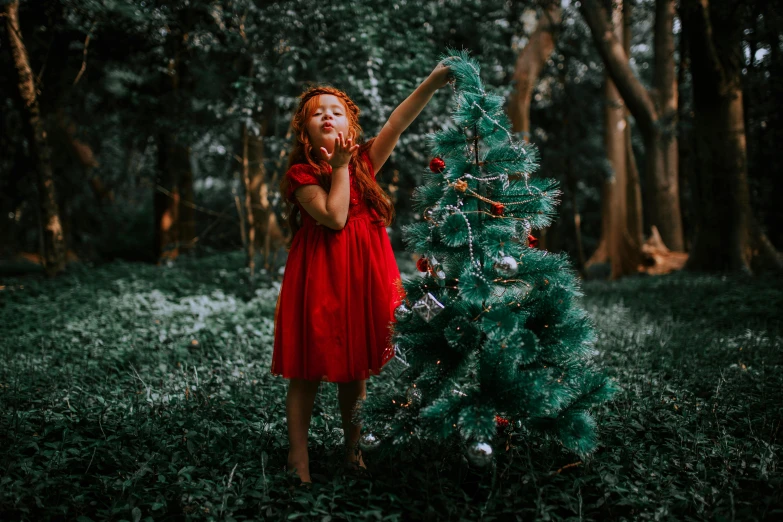 a woman in red is holding her hands up in front of a christmas tree