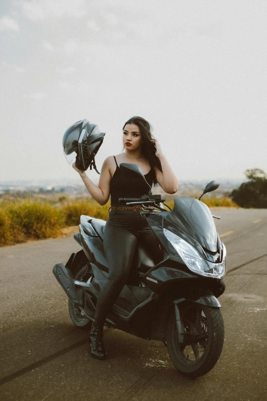 woman wearing leather clothes holding onto a motorcycle