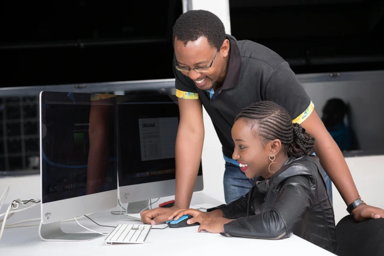 two people sitting at a desk using a computer