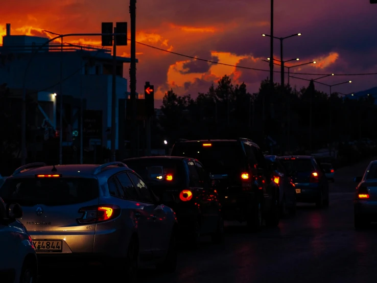 a city street lined with parked cars under lights