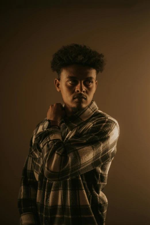 a young man wearing a shirt standing next to a wall