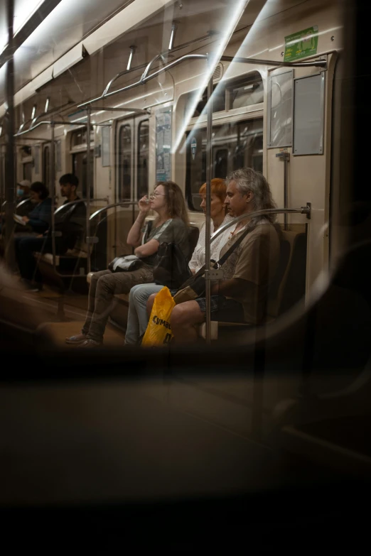 three people sitting next to each other on a subway