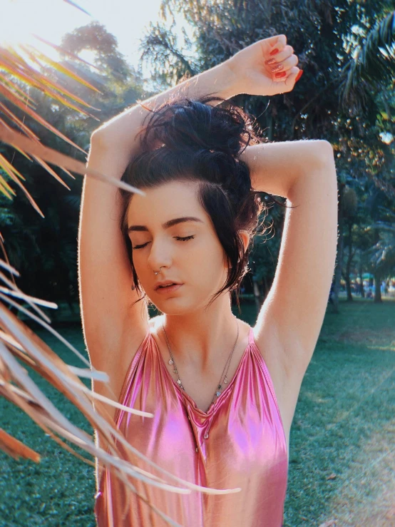 a girl in a pink bathing suit is standing by some grass