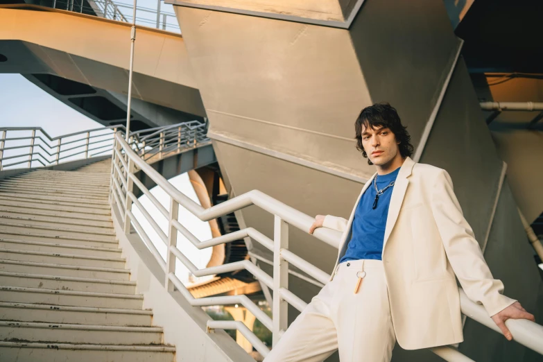 the man in a suit leans on a rail