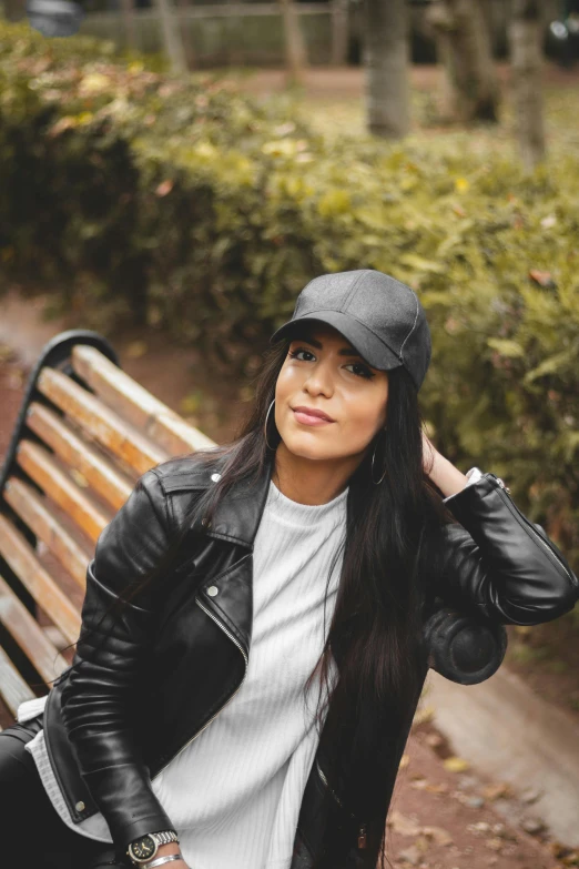 a woman sitting on a park bench with a black hat