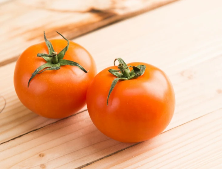 three tomatoes sit together on the table