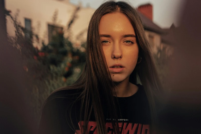 a girl with long hair sitting outside near a tree