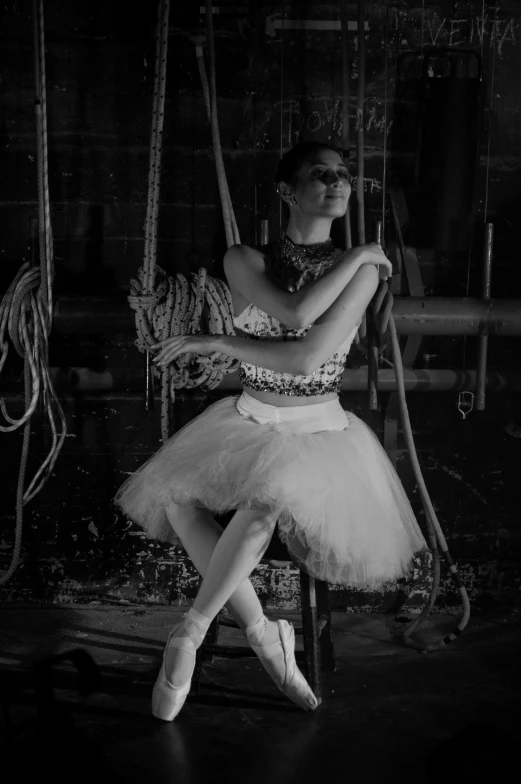 black and white po of woman dressed in ballet attire on swing