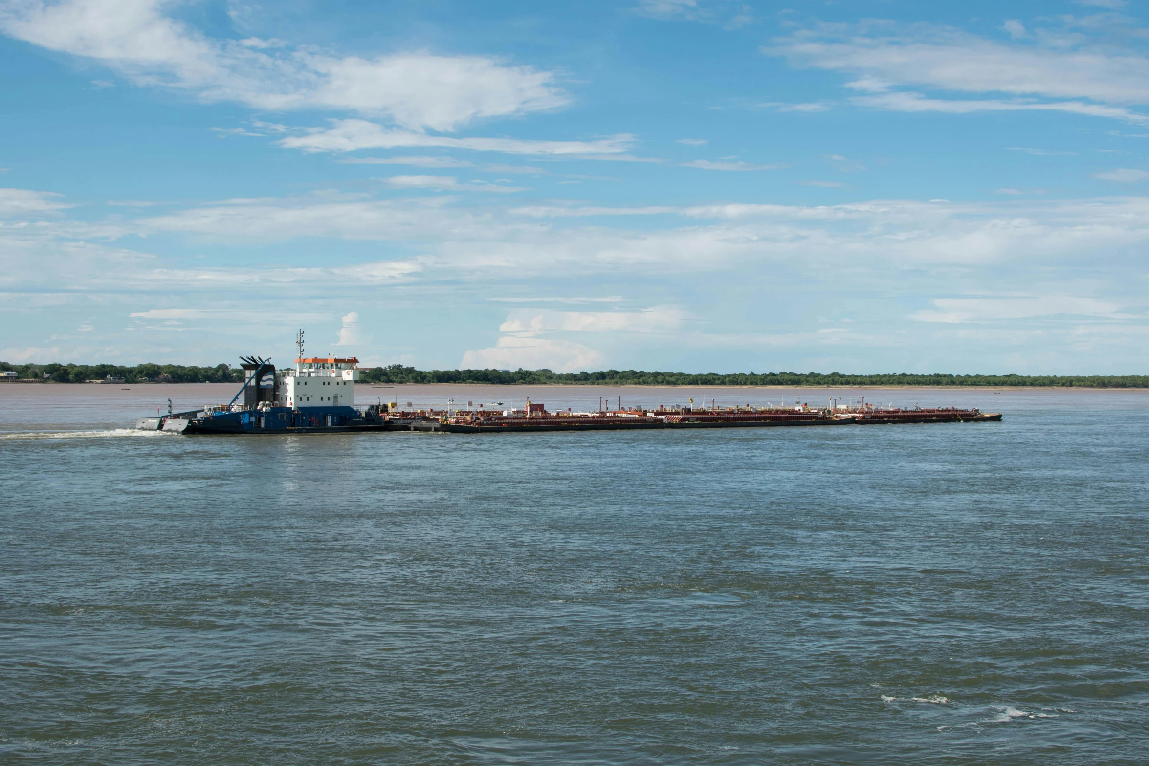 a barge traveling in the water with a small boat passing behind it