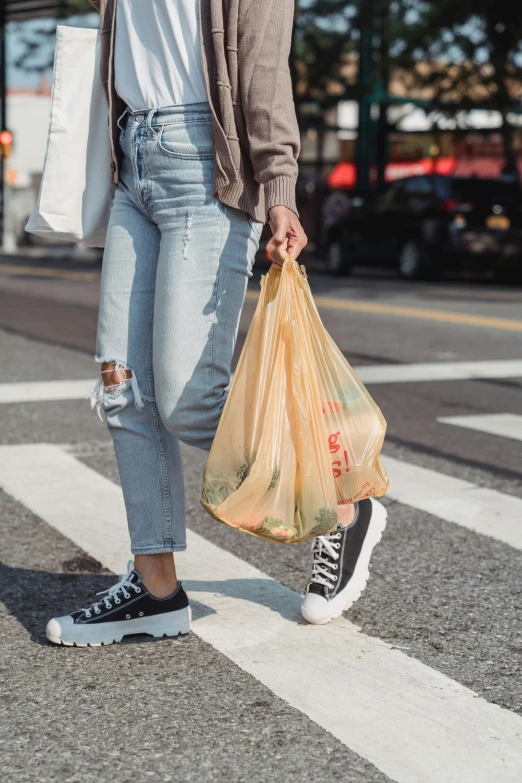 the woman is carrying a bag across the street