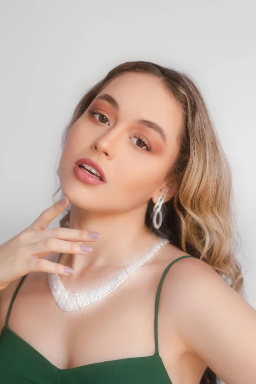 a woman in a green dress posing with a white necklace