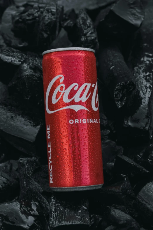 a coca - cola can on a pile of charcoals