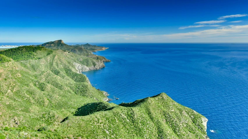 an ocean coast that has lush green hills