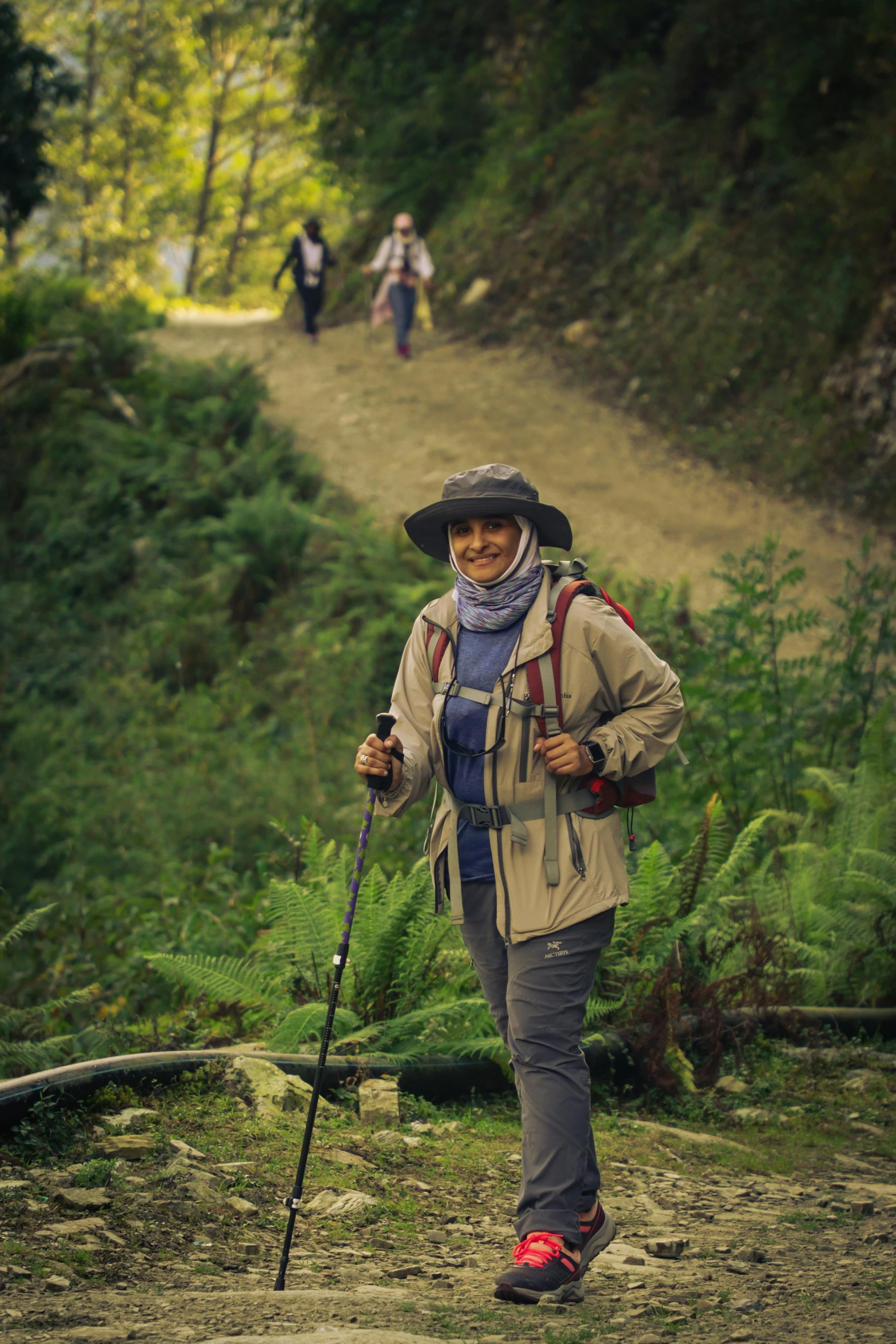 a woman with a backpack and hiking gear stands on a trail in a wooded area