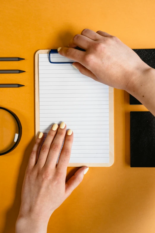 a hand with manicured nails holding a notebook