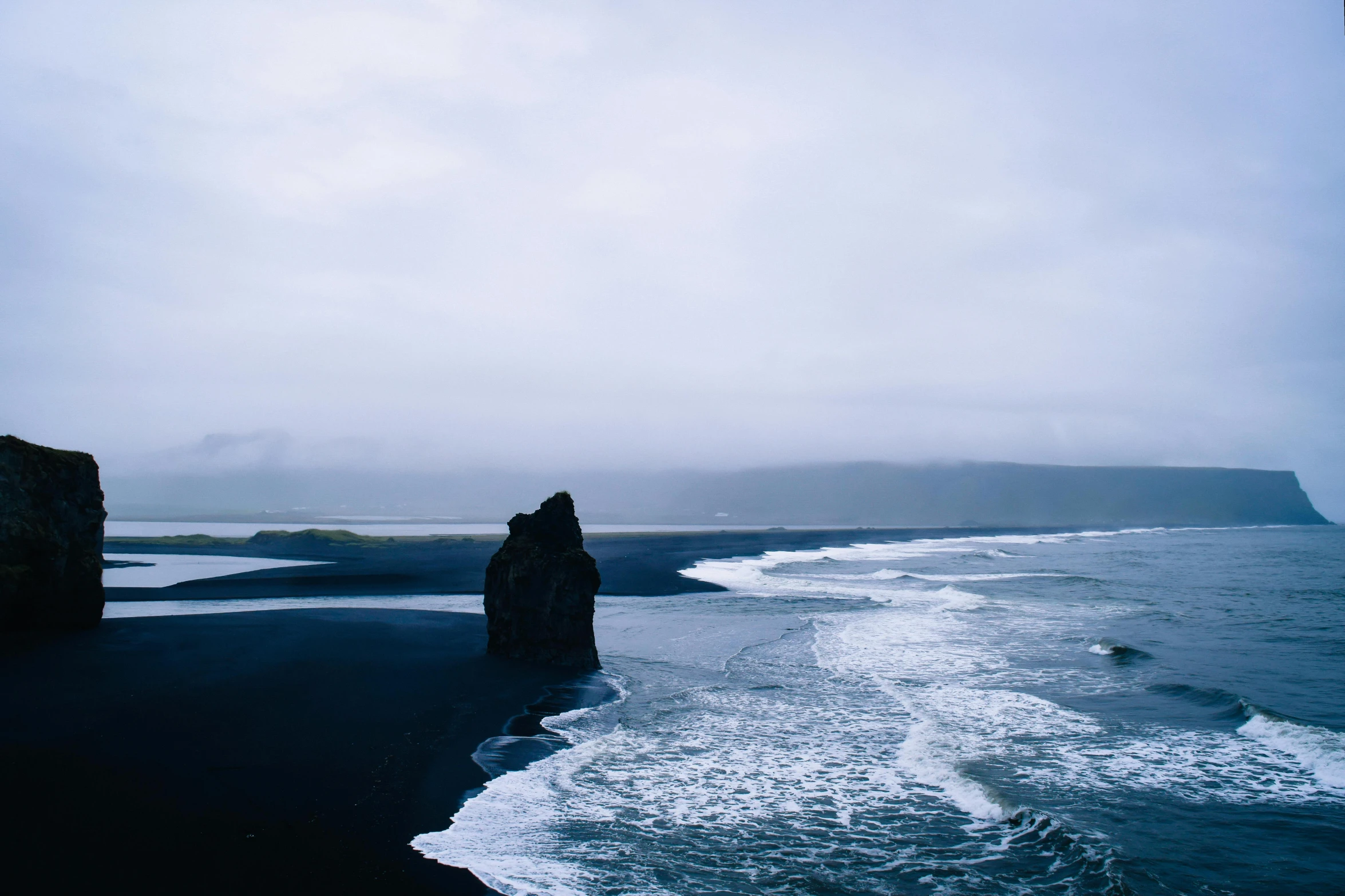 a very tall cliff at the ocean by the water